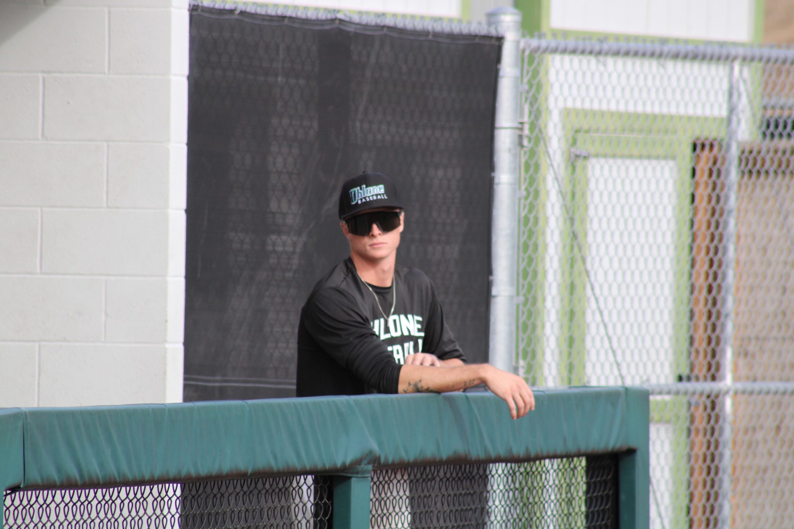 A man wearing a black tshirt standing near the fence
